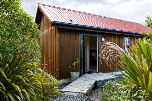 a small wooden house with a pathway leading to the door at The Hideout in Mangawhai