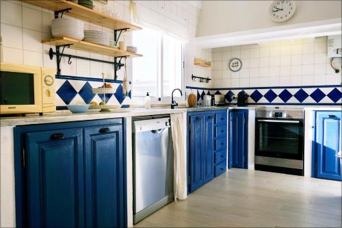 a blue kitchen with blue cabinets and appliances at Casa da Praia - Manta Rota in Manta Rota