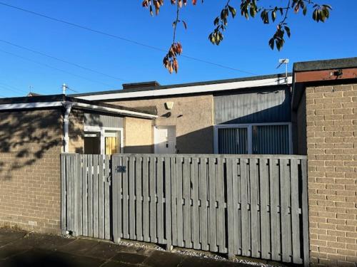 a white fence in front of a brick house at One Bedroom Bungalow Loanhead, Midlothian, Nr Edinburgh in Loanhead