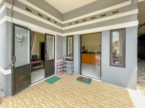 a living room with a wall of glass doors at Wisma Air Mancur Malang Mitra RedDoorz in Malang