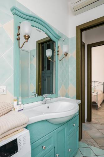 a bathroom with a blue sink and a mirror at Villetta Bouganville in Budoni