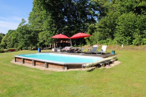 - une piscine avec 2 parasols, 2 chaises et une table dans l'établissement La grande foret, à Saint-Jouvent