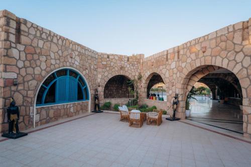 a stone building with a patio with tables and chairs at Seti Abu Simbel Lake Resort in Abu Simbel