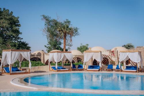 a pool at a resort with chairs and umbrellas at Seti Abu Simbel Lake Resort in Abu Simbel