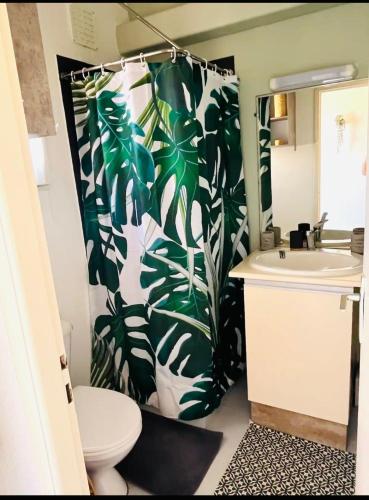 La salle de bains est pourvue d'un rideau de douche à motifs verts et blancs. dans l'établissement L Aphrodite Studio Village Naturiste, à Port-Leucate