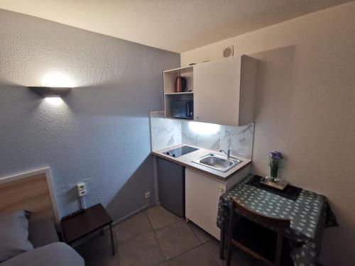 a small kitchen with a sink and a table at Appart Hotel La Defense in Courbevoie