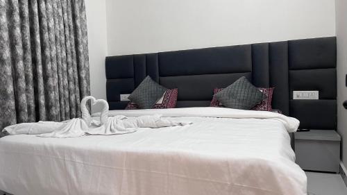 a white bed with a black headboard and white sheets at Mithila - A Lovely & Peaceful 3 BHK Villa in Orchha