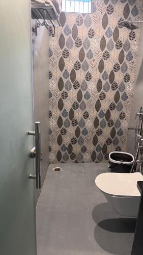 a bathroom with a shower with a toilet and a tile wall at Mithila - A Lovely & Peaceful 3 BHK Villa in Orchha