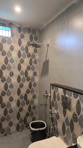 a bathroom with a toilet and a tile wall at Mithila - A Lovely & Peaceful 3 BHK Villa in Orchha