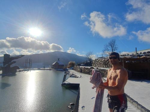 a shirtless man standing next to a swimming pool at Bioferienhof Brückler in Laussa