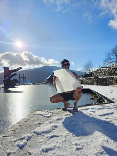 a man is holding a surfboard in the snow at Bioferienhof Brückler in Laussa