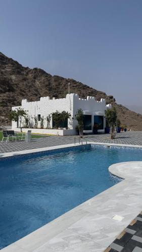 a swimming pool in front of a white building at Private farmstay BBQ and pool for Groups in Sharm