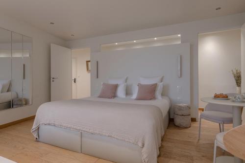 a bedroom with a large white bed with pink pillows at MiHotel Le Gourguillon in Lyon