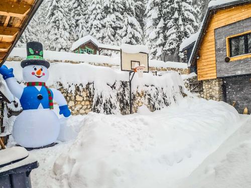 a snowman in front of a house in the snow at Vila Bašić Vlašić Spa Apartman JELEN in Vlasic