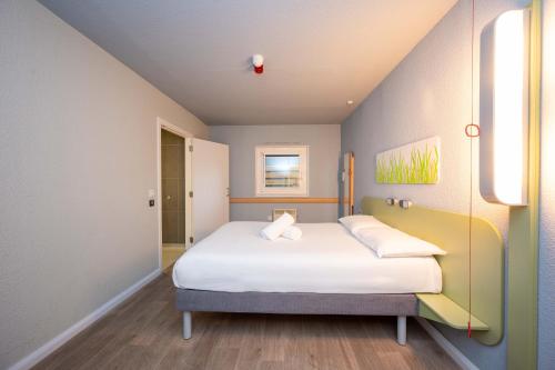 a bedroom with a bed with white sheets and pillows at ibis budget London Barking in Barking