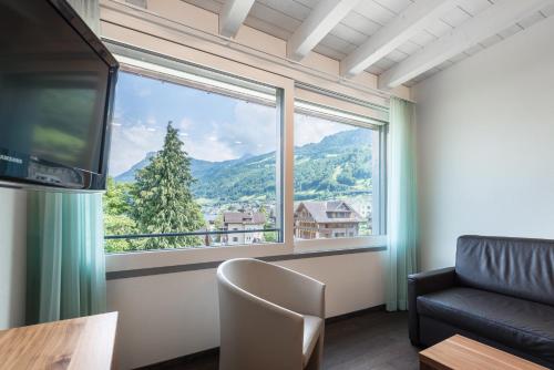 a living room with a large window and a couch at Superior Hotel Nidwaldnerhof in Beckenried