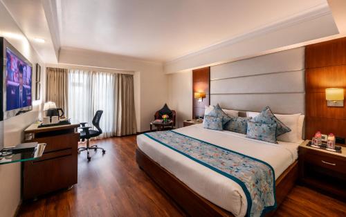 a hotel room with a large bed and a desk at Lords Plaza Jaipur in Jaipur