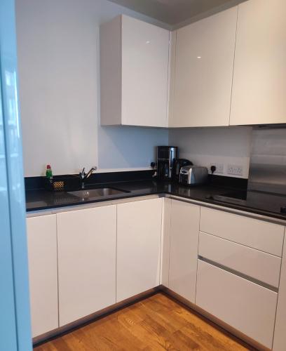 a kitchen with white cabinets and a sink at Modern Hi-rse 1bedroom Apartment in Woolwich