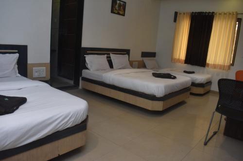 a room with three beds in a room at HOTEL SAI VISHVA KARMA in Shirdi