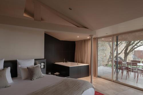 a bedroom with a bed and a bathroom with a tub at MiHotel Le Gourguillon in Lyon