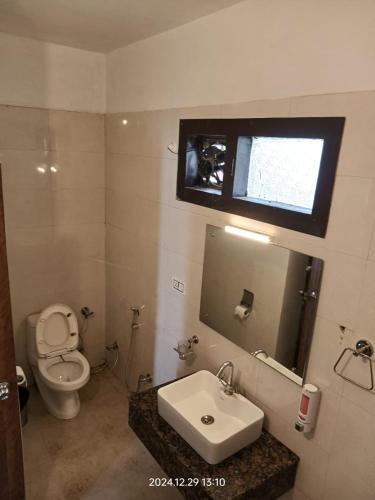 a bathroom with a toilet and a sink and a mirror at Shikha Resort Ewentbliz in Bhīm Tāl