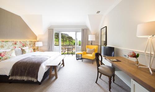 a hotel room with a large bed and a desk and chairs at Mont Rochelle in Franschhoek