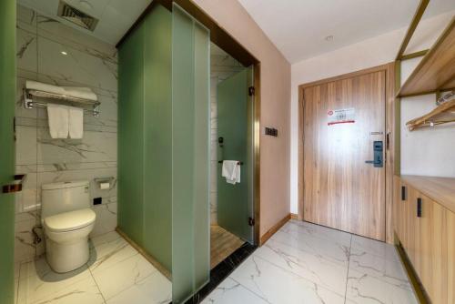 a bathroom with a toilet and a green wall at 厦门中山海滨酒店 in Xiamen
