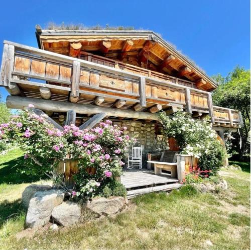 ein Haus mit einer Terrasse und Blumen davor in der Unterkunft Magnifique chalet bois pour 16 personnes à 1600m in La Cabanasse