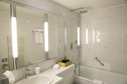 a bathroom with a tub and a sink and a mirror at Hotel Hirschen am See in Meilen