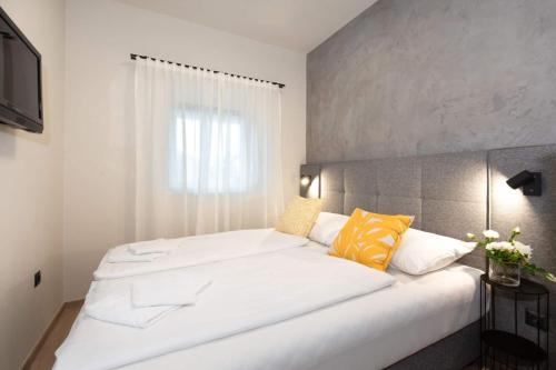 a bedroom with a large white bed with yellow pillows at Villa LuiSole in Krk
