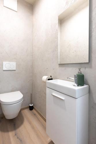 a white bathroom with a toilet and a sink at Villa LuiSole in Krk