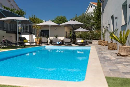 a swimming pool in a yard with umbrellas at Villa LuiSole in Krk