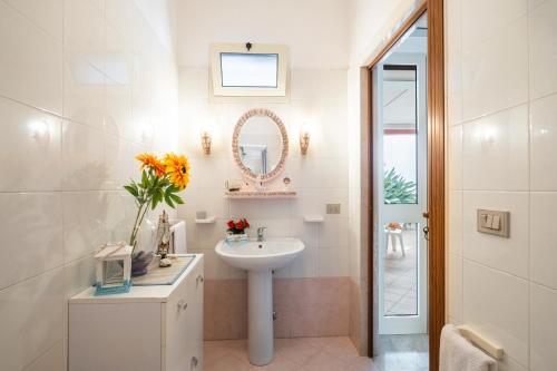 a white bathroom with a sink and a mirror at Villetta Fronte Mare White Beach in Porto Cesareo