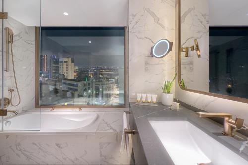 a bathroom with a large tub and a window at Signia by Hilton in Amman