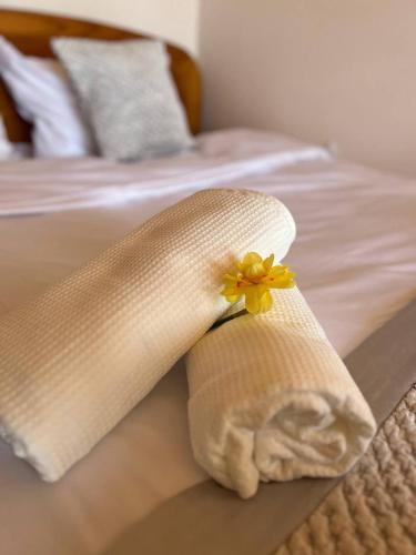 a white towel with a yellow flower on a bed at Villa Green in Molėtai