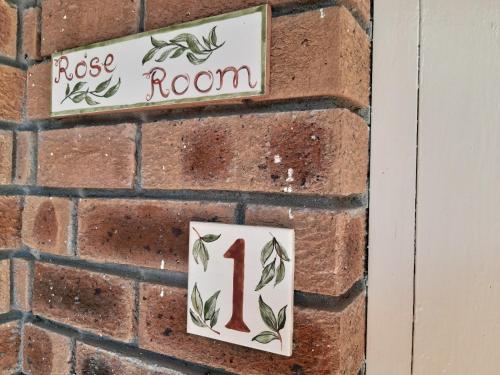 a brick wall with signs that say roses room at Rustic Manor Guest House in Tokai