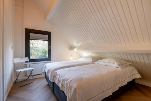 ein Schlafzimmer mit einem großen weißen Bett und einem Fenster in der Unterkunft Groenendijk Verhuur Vakantiehuis Jonas Burgh-Haamstede in Burgh Haamstede