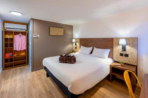 a hotel room with a large white bed and a table at greet Hotel Chatellerault in Châtellerault