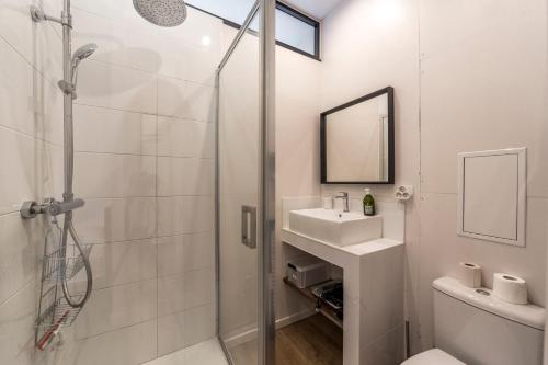 une salle de bain blanche avec une douche et un lavabo dans l'établissement Le petit Barret du 8ème AIL, à Lyon