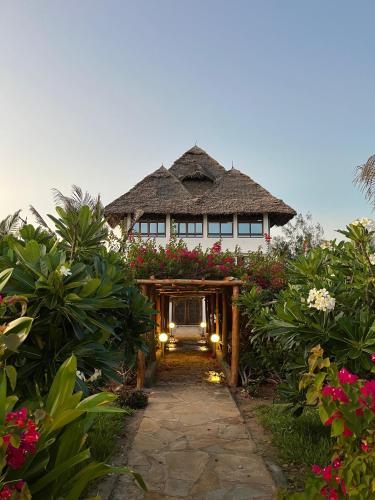 a house with a pathway leading to it with flowers at Maua Room at Lulu Sands in Watamu