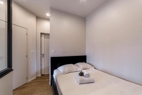 - une chambre blanche avec un lit et deux oreillers dans l'établissement Le petit Barret du 8ème AIL, à Lyon