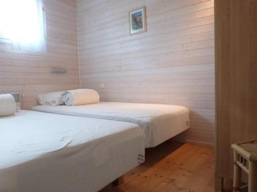 deux lits dans une chambre aux murs en bois dans l'établissement GASMIM64 Chalet californien pour 6 personnes Proche St-Tropez, à Gassin