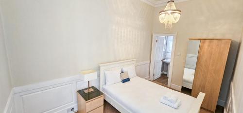 a small bedroom with a bed and a chandelier at Russel House - 4 Bedroom - The Royal Mile in Edinburgh