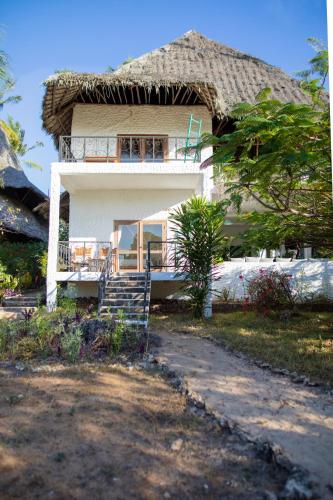 a house with a thatched roof and a staircase in front at Temple Point Resort in Watamu