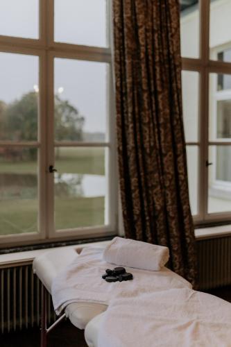 a bed in a room with two windows at B&B Kasteel Den Tip in Arendonk