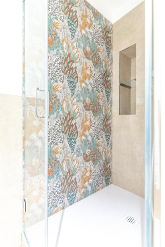 a shower with a glass door with a floral wallpaper at Lumamè Resort B&B in Montefiore Conca