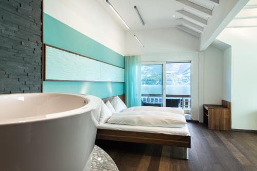 a bathroom with a bath tub and a bed at Superior Hotel Nidwaldnerhof in Beckenried