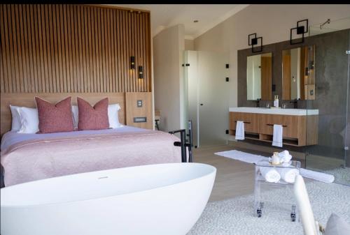 a bedroom with a large bed and a bath tub at La-Ngwenya Serenite in Warmbaths
