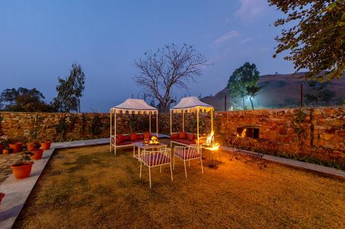 a backyard with a table and chairs and a stone wall at ELIVAAS Amber Royale 3 BHK with Pvt Pool & Terrace in Udaipur