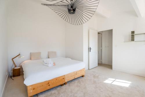 ein Schlafzimmer mit einem weißen Bett und einem großen Kronleuchter in der Unterkunft Grand Duplex T2 - Plein coeur historique et du port in Marseille